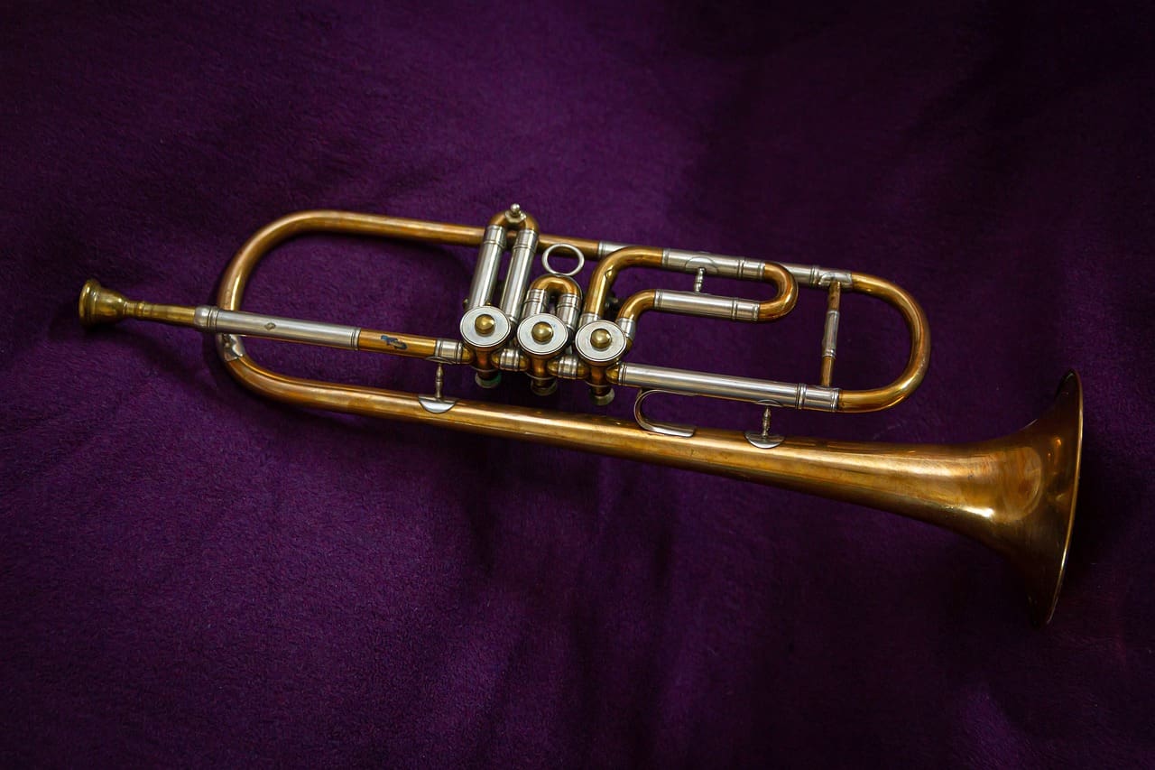 A trombone sitting on top of purple cloth.